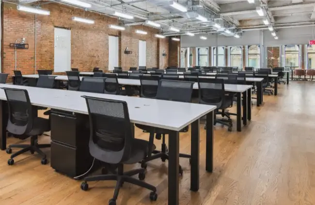 Rows of desks and chairs in very large open coworking area