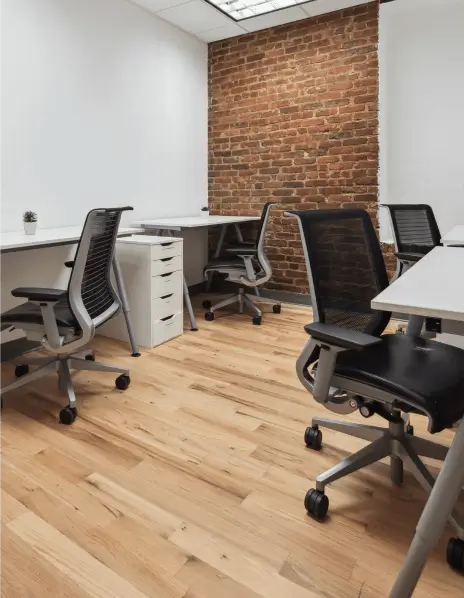 Team suite with 4 desks and chairs. Beautiful brick wall and white painted walls surround.