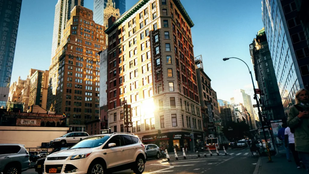 Busy New York City street near Flatiron lined with tall buildings and cars in sunlight. An ideal location for team office space in Manhattan.