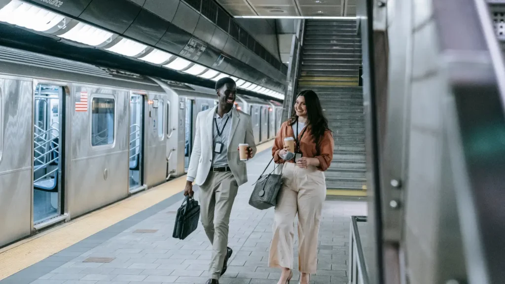 Two professionals walking with coffee in a subway station.