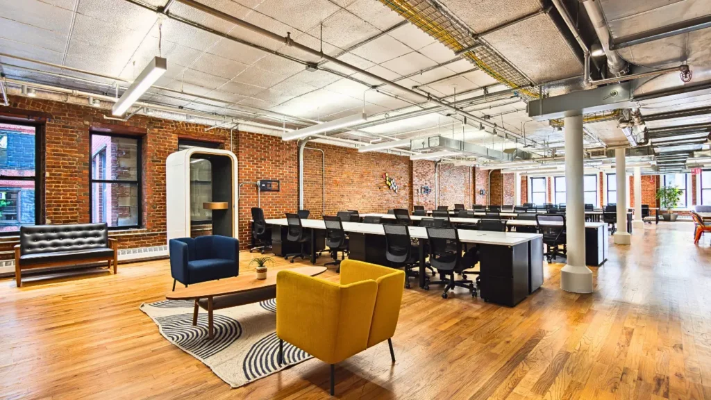 Modern coworking lounge with colorful chairs and shared workstations.