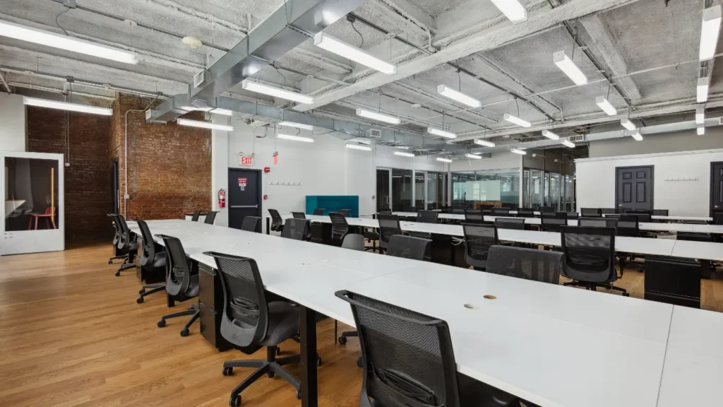 Large open coworking office with long rows of workstations.