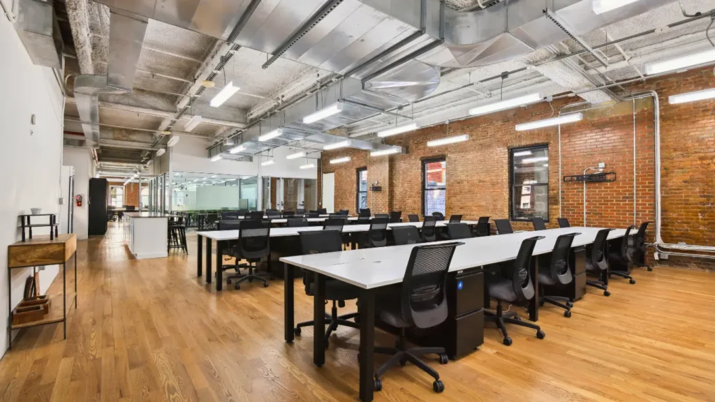 Spacious open-plan coworking area with rows of desks.