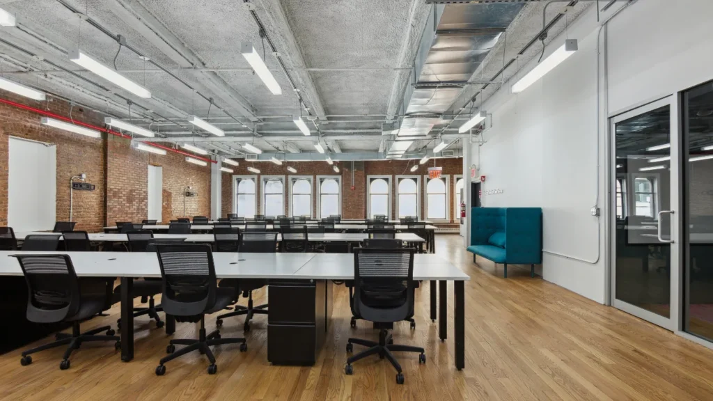 Shared coworking area for coworking day pass member with open desks and brick walls.