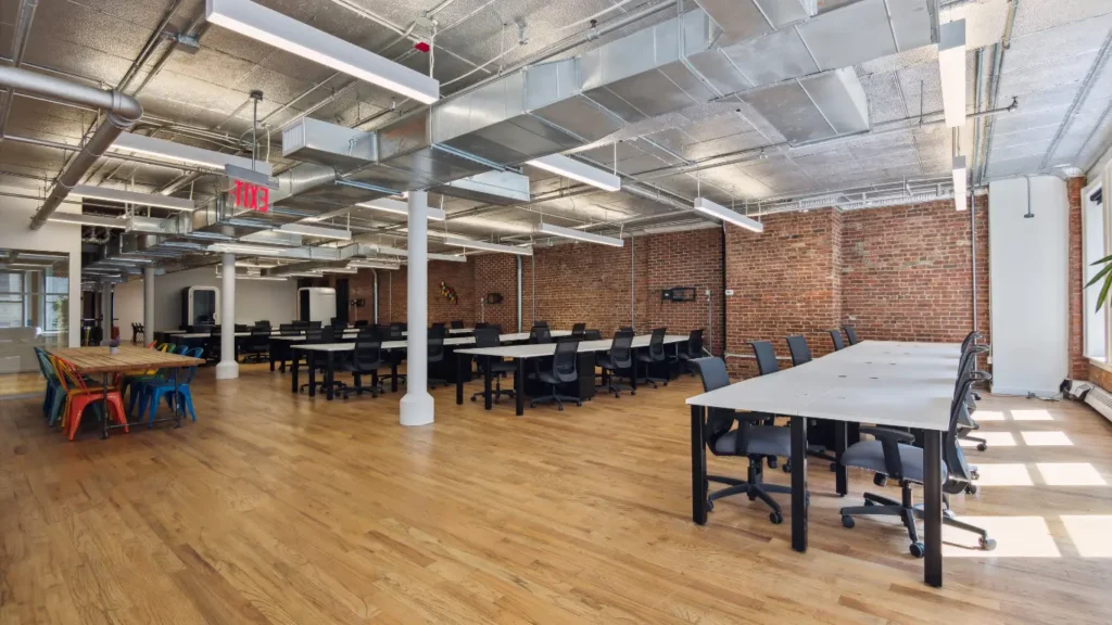 Spacious coworking area in Chelsea with long shared desks and exposed brick walls