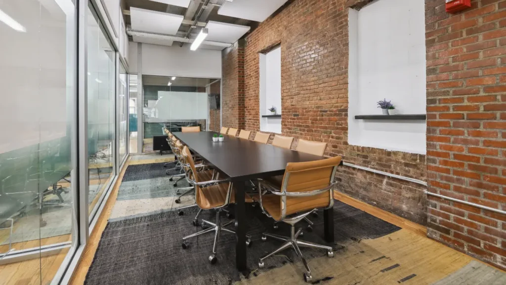 Modern meeting room with long conference table and tan chairs.