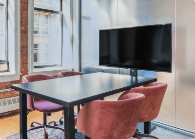 4 person meeting room with comfortable looking chairs, TV, and meeting amenities visible.