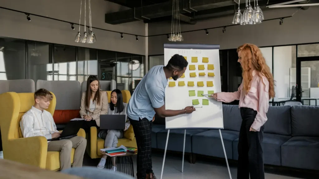 Team in modern office lounge collaborating with sticky notes on a flip chart.