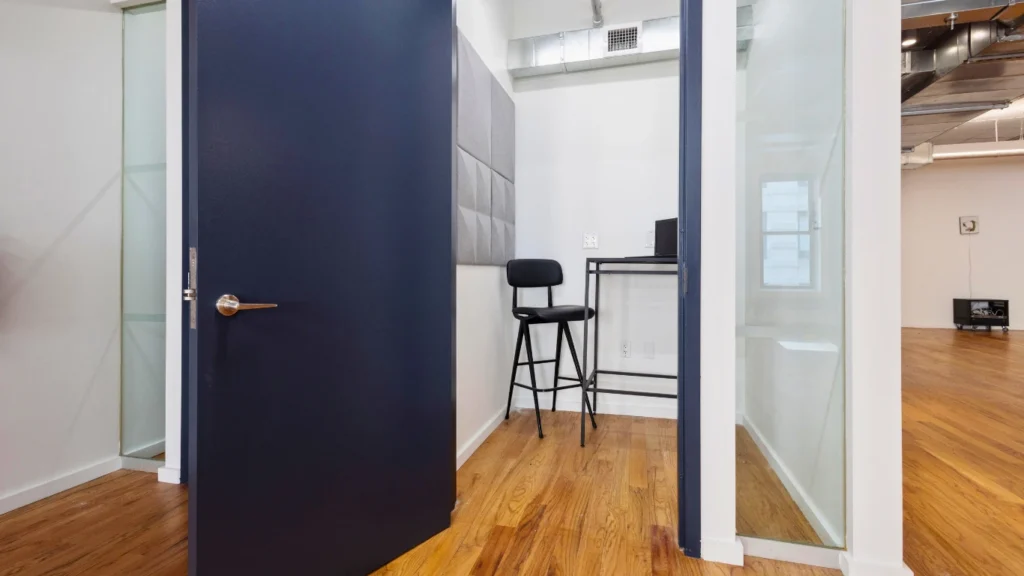 Private phone booth workspace with a stool.