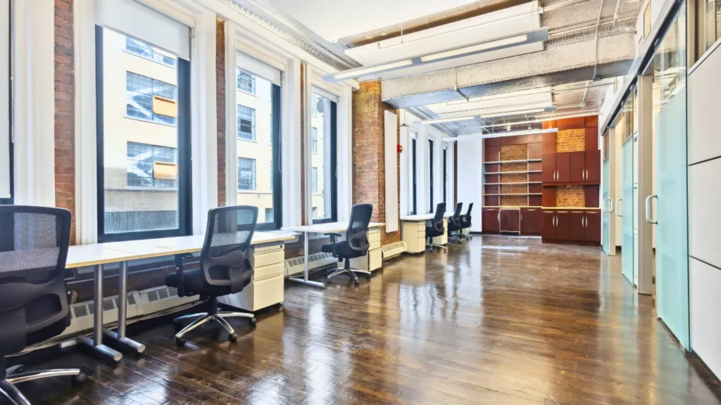 Row of dedicated desks with ergonomic chairs in a sunny office.